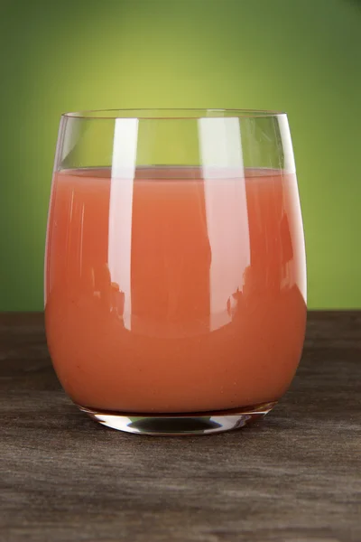 Glass of fresh juice on table on green background — Stock Photo, Image