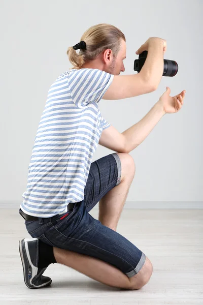 Handsome photographer with camera, on gray background — Stock Photo, Image