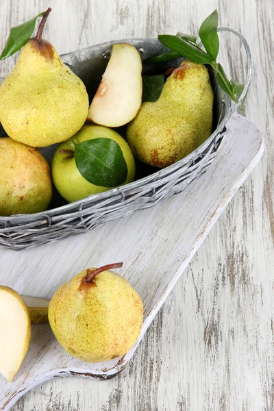 Pears in basket on board on wooden table — Stock Photo, Image