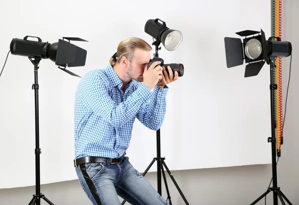 Schöner Fotograf mit Kamera bei der Arbeit, auf Studiohintergrund — Stockfoto