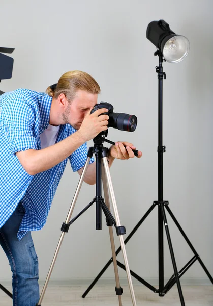 Stilig fotograf med kamera på arbetar, på foto studio bakgrund — Stockfoto