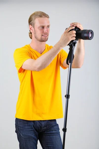 Fotógrafo bonito com câmera em monopod, em fundo cinza — Fotografia de Stock