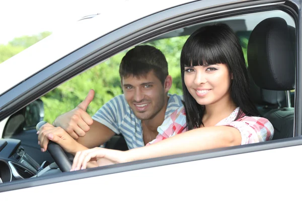 Счастливая молодая пара за рулем автомобиля — стоковое фото