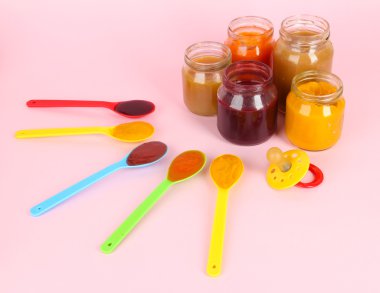 Bebek püresi pembe bir arka plan üzerinde meme kaşıklarla içinde