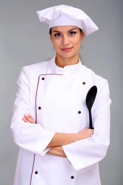 Portrait of young woman chef on grey background — Stock Photo, Image