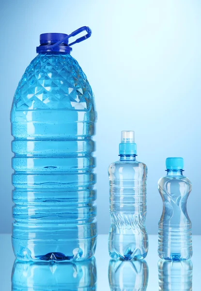 Diferentes botellas de agua sobre fondo azul —  Fotos de Stock