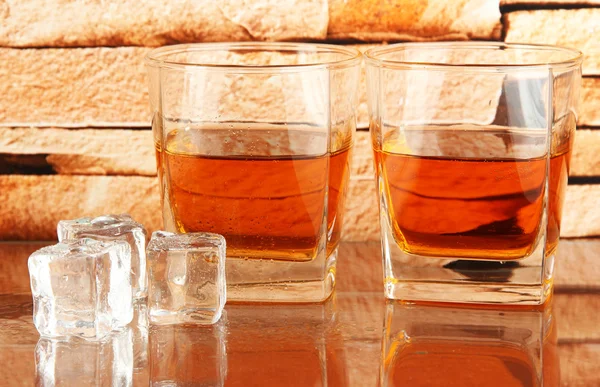 Glazen whiskey en ijs op bakstenen muur achtergrond — Stockfoto