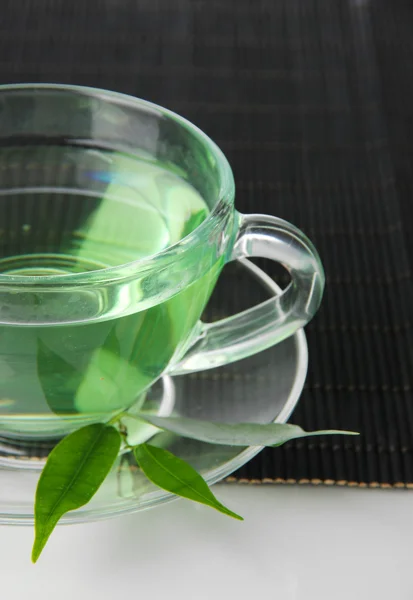 Taza transparente de té verde en estera de bambú, aislada en blanco —  Fotos de Stock