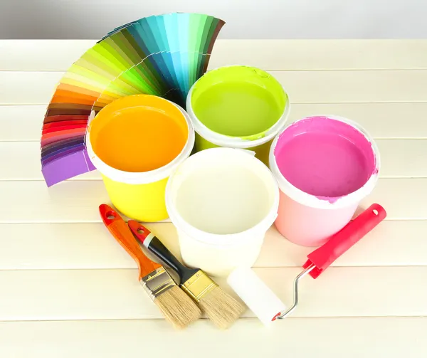 Set for painting: paint pots, brushes, paint-roller on white wooden table — Stock Photo, Image