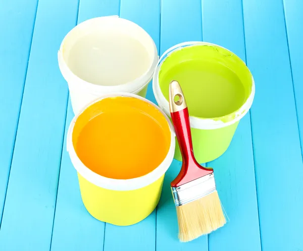 Set for painting: paint pots, brushes on blue wooden table — Stock Photo, Image