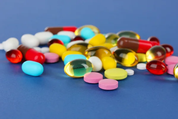 Assortment of pills, tablets and capsules on blue background — Stock Photo, Image