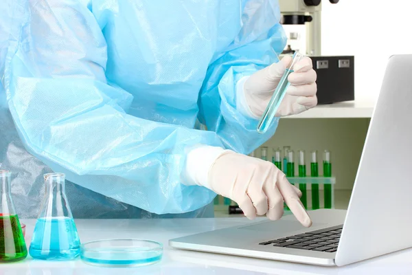 Scientist entering data on laptop computer with test tube close up — Stock Photo, Image