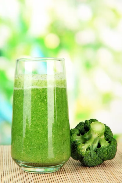 Glass of broccoli juice, on bamboo mat, on green background — Stock Photo, Image