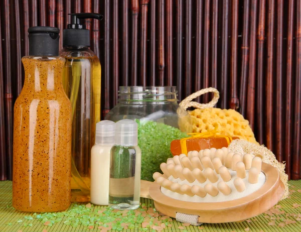 Limpiador, cepillo y cosméticos para ducha sobre mesa sobre fondo de bambú —  Fotos de Stock