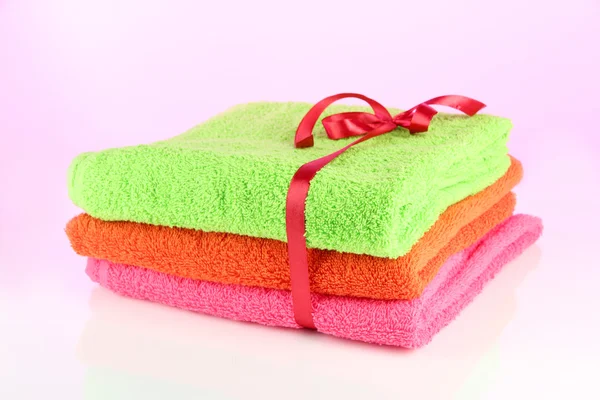 Towels tied with ribbon on light pink background — Stock Photo, Image