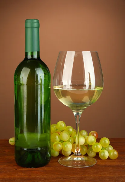 Composition of wine bottle, glass of white wine, grape on color background — Stock Photo, Image