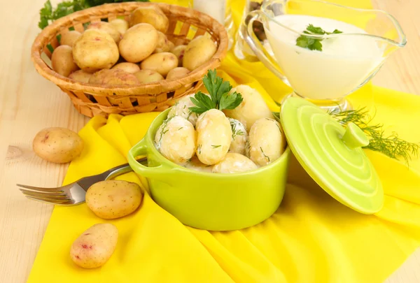 Anbudsförfarande unga potatis med gräddfil och örter i stekpanna på träbord närbild — Stockfoto