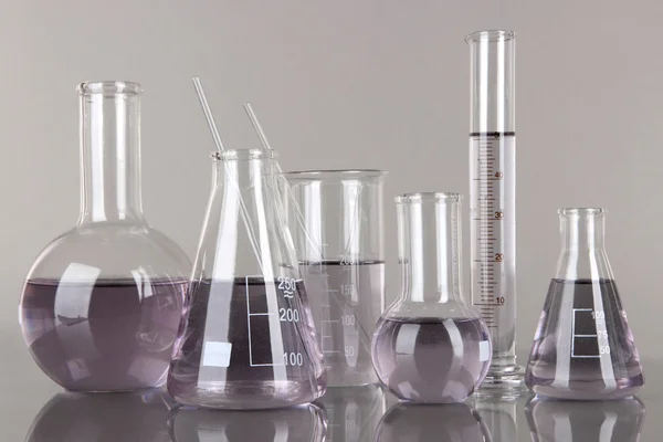 Test-tubes with light purple liquid on gray background — Stock Photo, Image