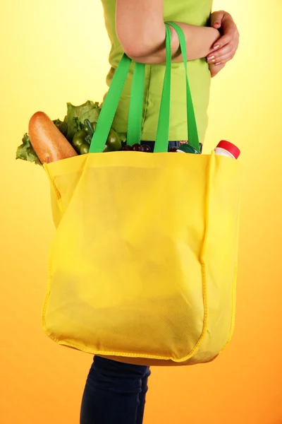 Meisje met boodschappentas op oranje achtergrond — Stockfoto