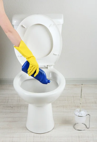 Mulher mão com spray garrafa de limpeza de um vaso sanitário em um banheiro — Fotografia de Stock
