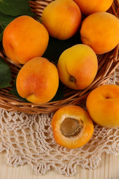 Apricots on wicker coasters on napkin on wooden table — Stock Photo, Image