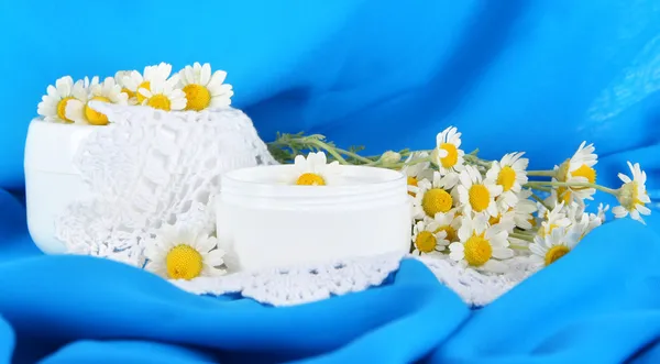 Cream with chamomile on napkin on blue fabric background — Stock Photo, Image