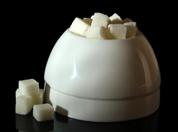 在黑色背景上的白色糖碗中的精制的糖 — 图库照片