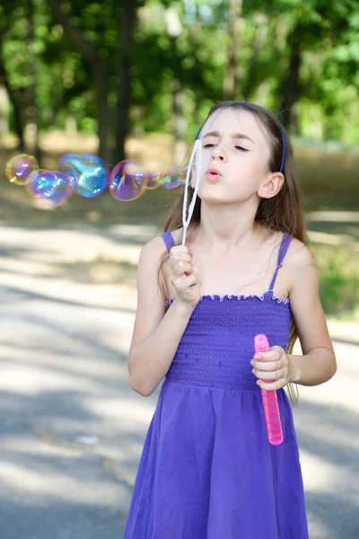 Leuk meisje blazen van zeepbellen buitenshuis — Stockfoto