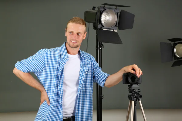 Schöner Fotograf mit Kamera bei der Arbeit, auf Studiohintergrund — Stockfoto