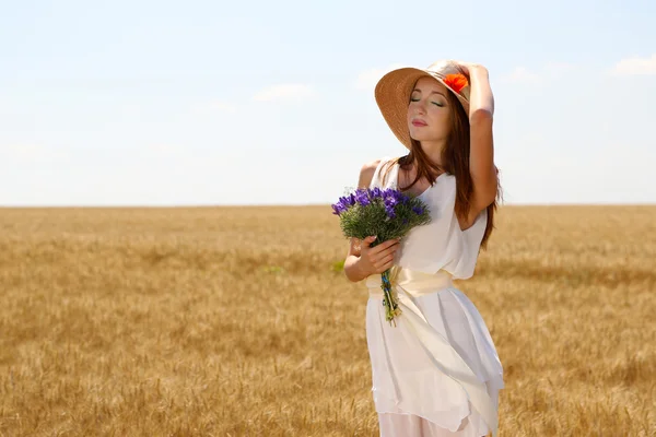 Ritratto di bella giovane donna con fiori nel campo — Foto Stock