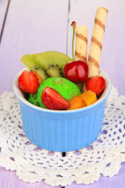Delicioso helado con frutas y bayas en un tazón sobre una mesa de madera — Foto de Stock