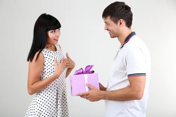 Hermosa pareja amorosa con regalo sobre fondo gris —  Fotos de Stock