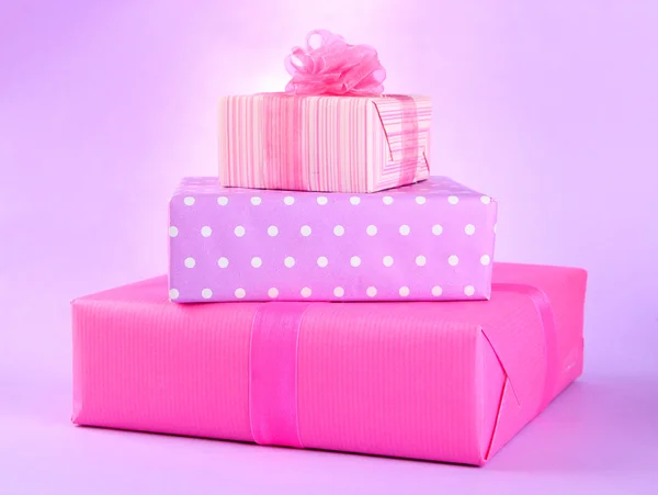 Bright gifts with bows on purple background — Stock Photo, Image