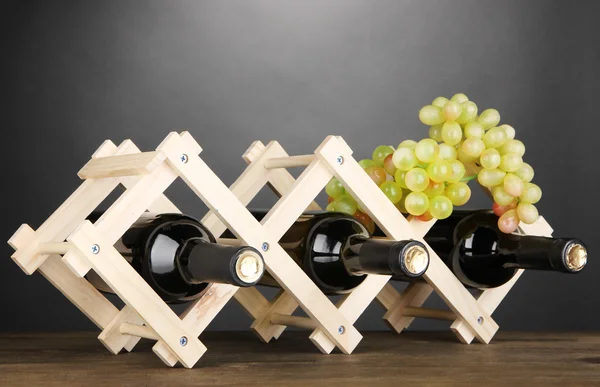 Bottiglie di vino poste su basamento in legno su fondo grigio — Foto Stock