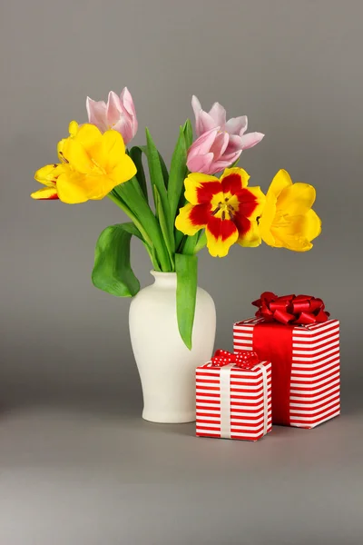 Piękne tulipany w wiaderku z prezentów na szarym tle — Zdjęcie stockowe