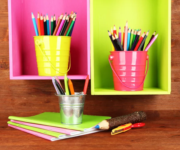 Färgglada pennor i hinkar på hyllorna på trä bakgrund — Stockfoto
