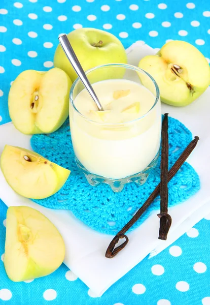 Iogurte delicioso em vidro com maçã na toalha de mesa azul — Fotografia de Stock