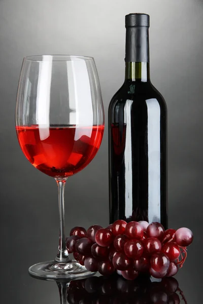 Verre à vin rouge et bouteille de vin sur fond gris — Photo