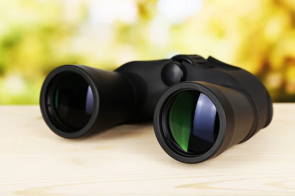 在绿色背景上的木桌上的黑色现代双筒望远镜 — 图库照片