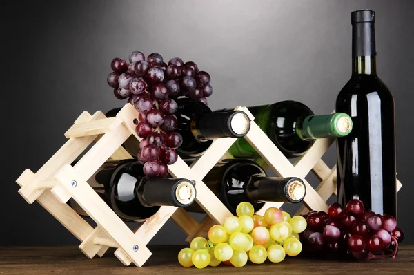 Botellas de vino colocadas sobre soporte de madera sobre fondo gris — Foto de Stock