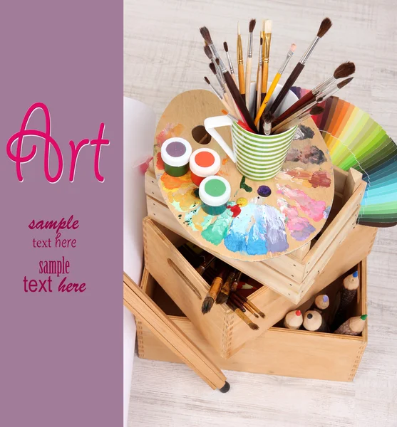 Wooden easel with clean paper and art supplies in room — Stock Photo, Image