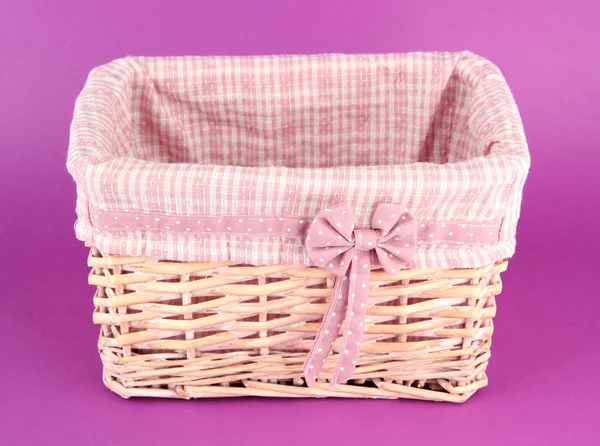 Wicket basket with pink fabric and bow, on color background — Stock Photo, Image