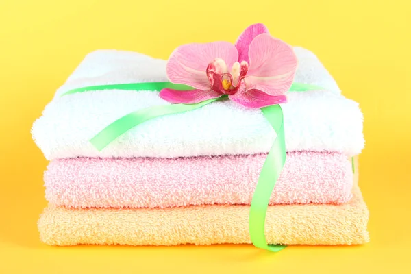 Towels tied with ribbon on yellow background — Stock Photo, Image