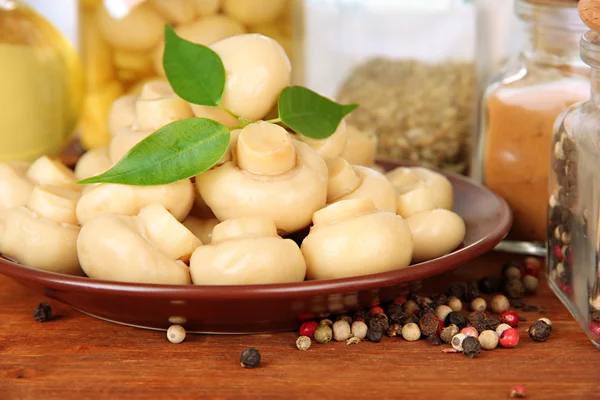 Composition of delicious marinated mushrooms, oil and spices on wooden table on bright background — Stock Photo, Image