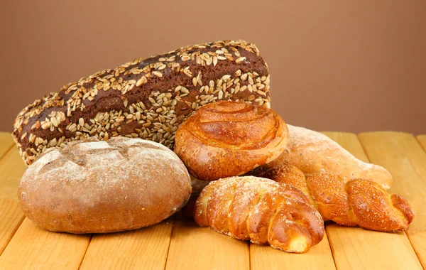 Composition with bread and rolls on wooden table, on color background — Stock Photo, Image