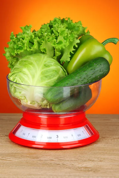 Fresh vegetables in scales on table on orange background — Stock Photo, Image