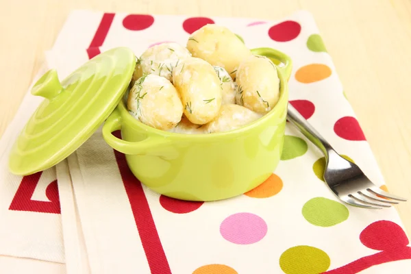 Tender young potatoes with sour cream and herbs in pan on wooden table close-up — Stock Photo, Image