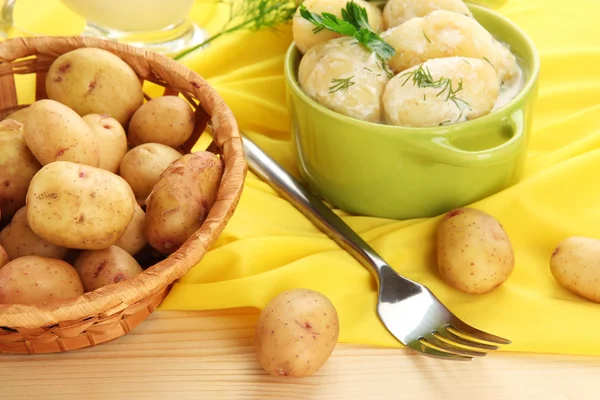 Inschrijving van jonge aardappelen met zure room en kruiden in pan op houten tafel close-up — Stockfoto