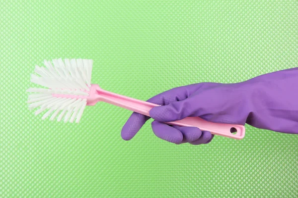 Toilet brush in hand on green background — Stock Photo, Image