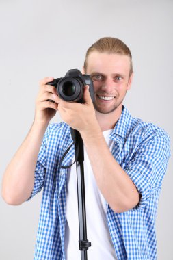 yakışıklı fotoğrafçı monopod gri arka plan üzerinde kamera ile